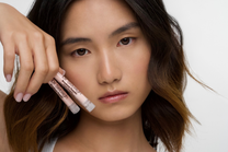 Model holding Dr Sebagh blackhead-removing powder skincare product close to face, a pore-refining exfoliating powder designed to help remove blackheads, unclog pores and smooth skin texture.
