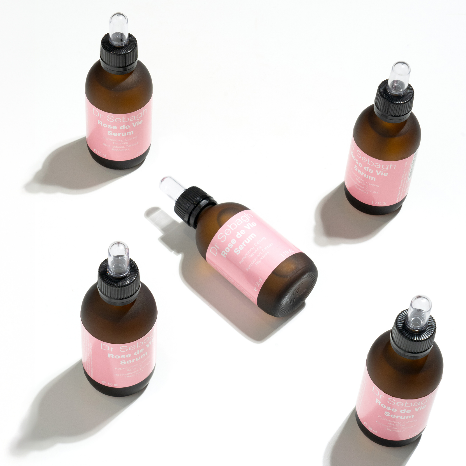Dr Sebagh Rose de Vie Serum professional size bottles arranged in a flat lay on a white background, showcasing luxury clinic-grade skincare with glass dropper packaging