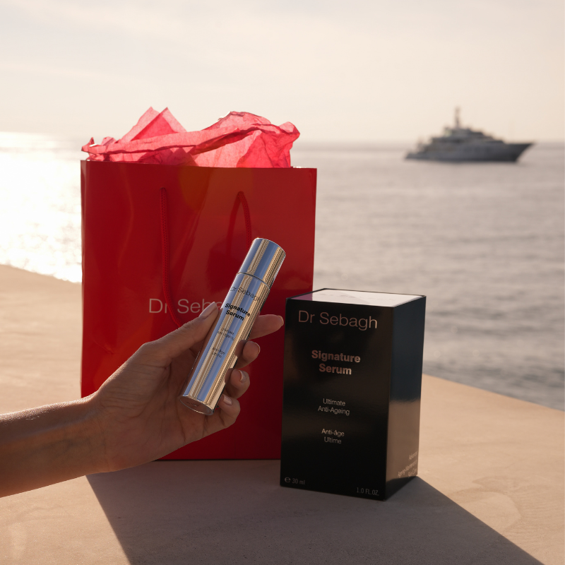 Dr Sebagh Signature Serum, luxury serum with gift bag and sea in the background