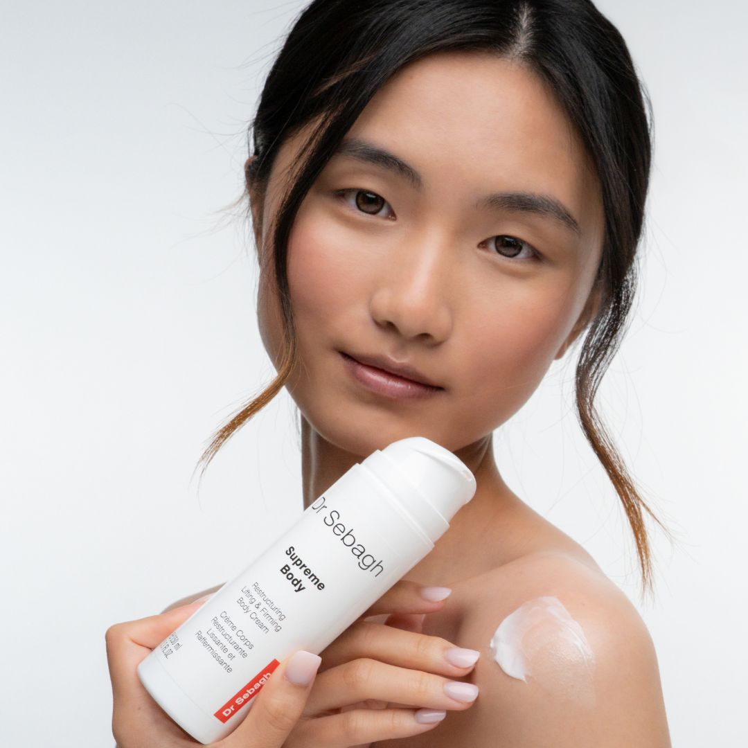 Woman holding a bottle of Sebagh Supreme Body product with a white background