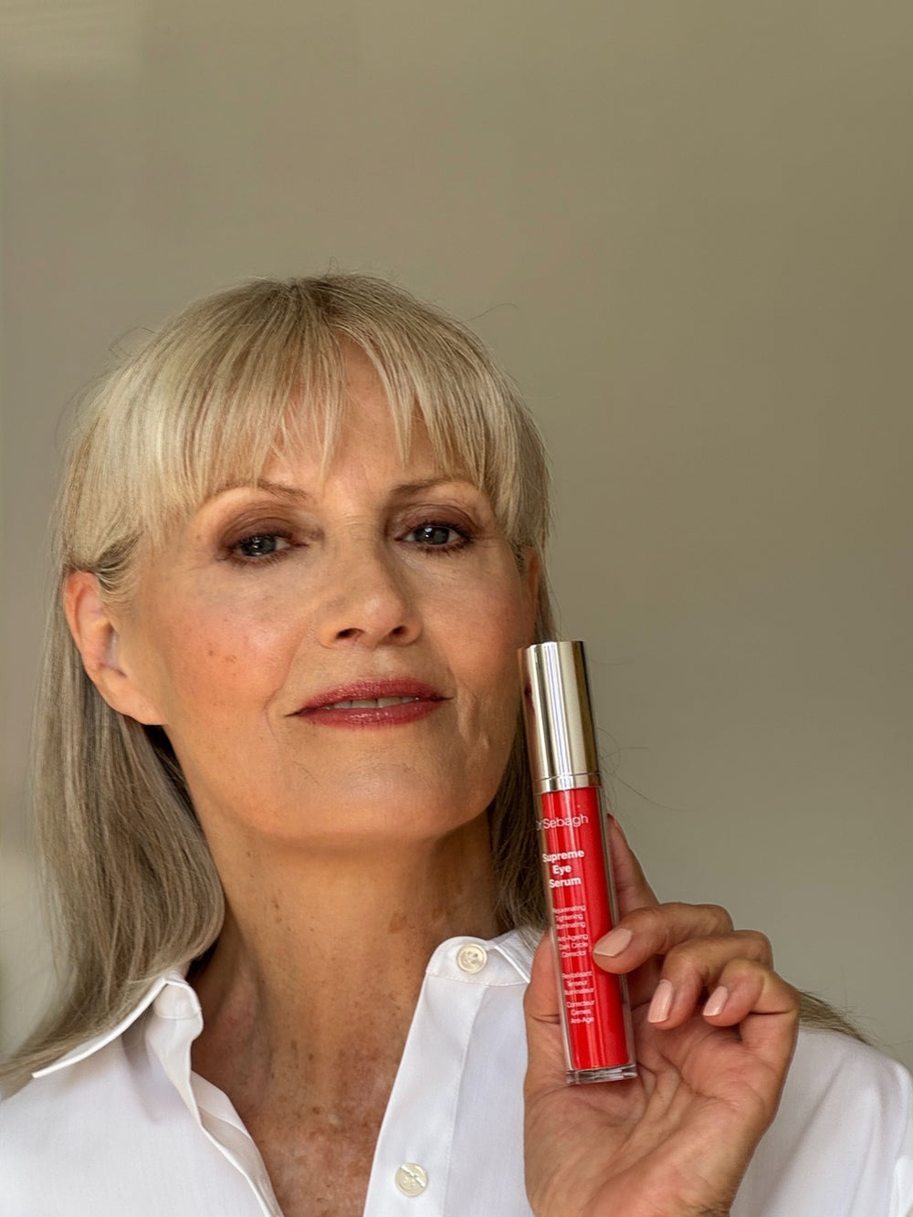 Woman holding Dr Sebagh Supreme Eye Serum against a neutral background