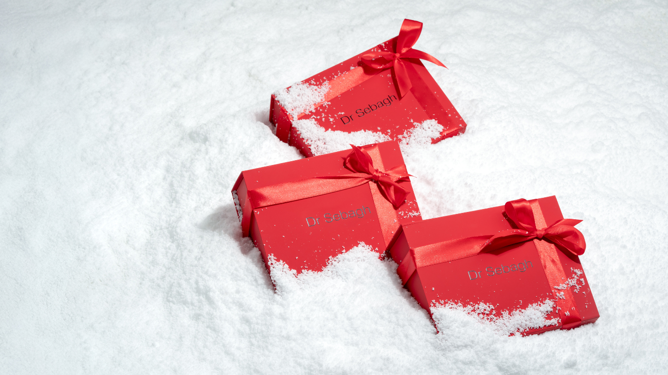 Dr Sebagh red Christmas gift boxes in snow, luxury skincare holiday presents with festive packaging.