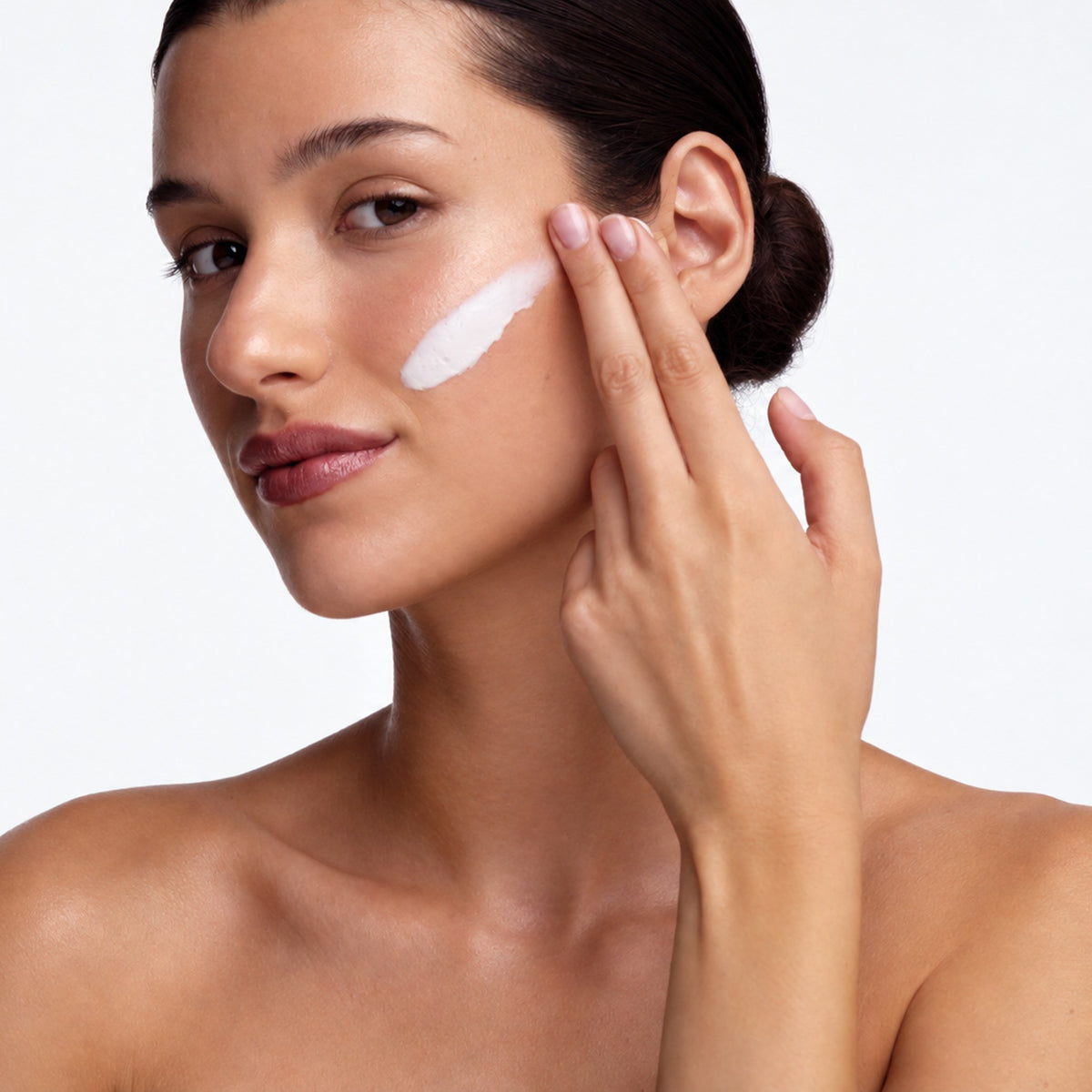 Model applying Dr Sebagh Skin Perfecting Mask to her cheek, showing the creamy mask texture