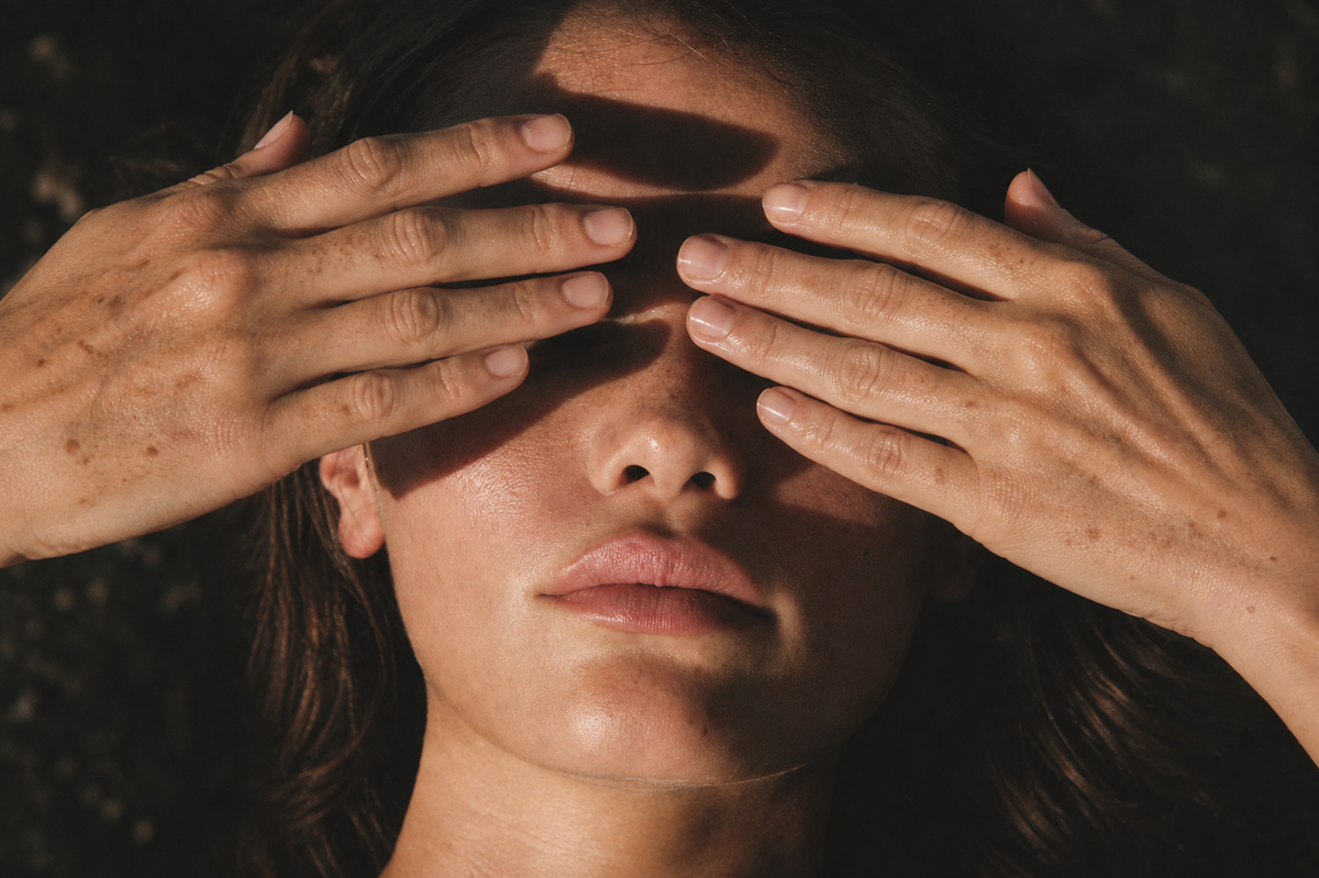 Age spots on the backs of the hands, raised to shield a face from direct sunlight