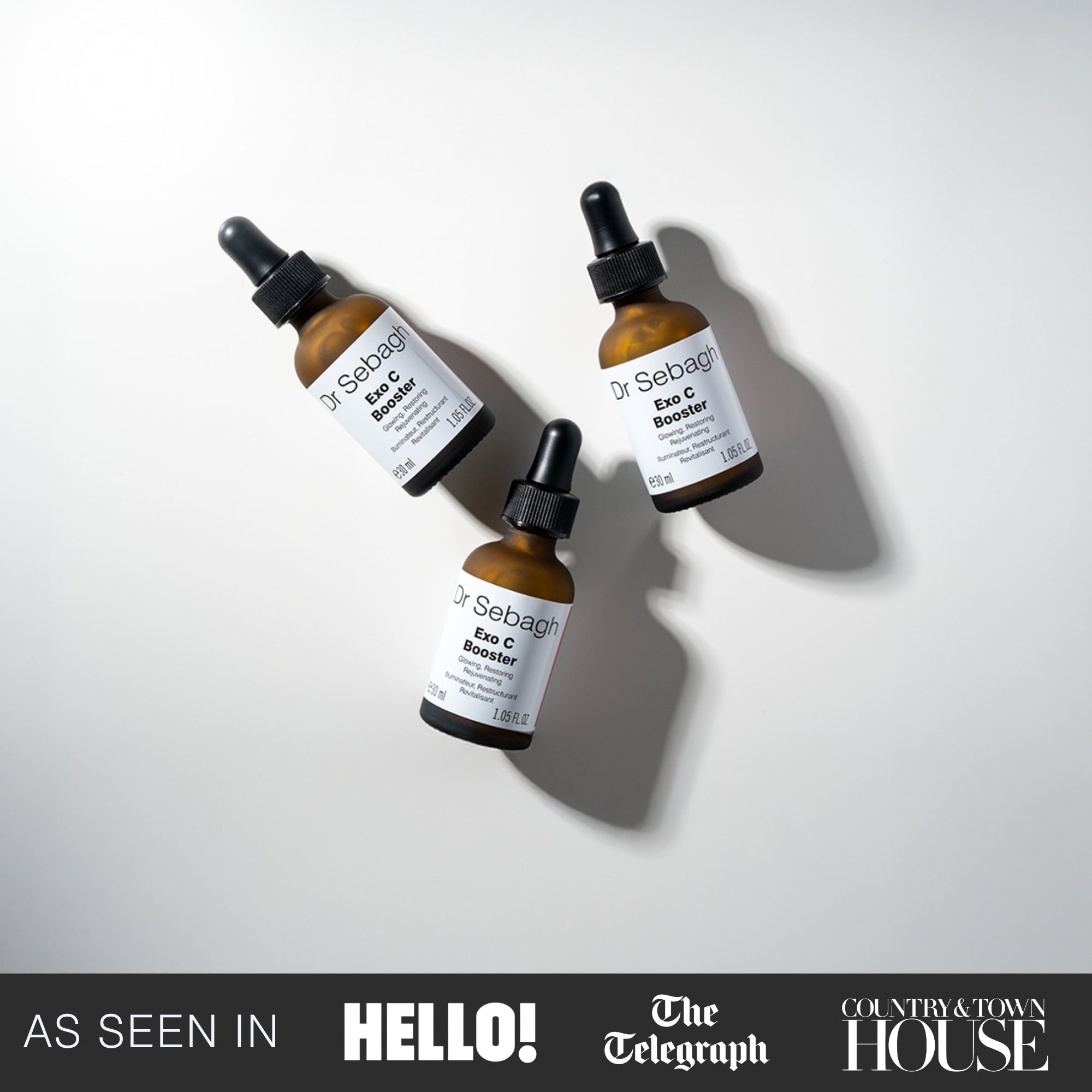 Three glass dropper bottles of Dr Sebagh's Exo C booster arranged diagonally on a light gray background with soft shadows. 