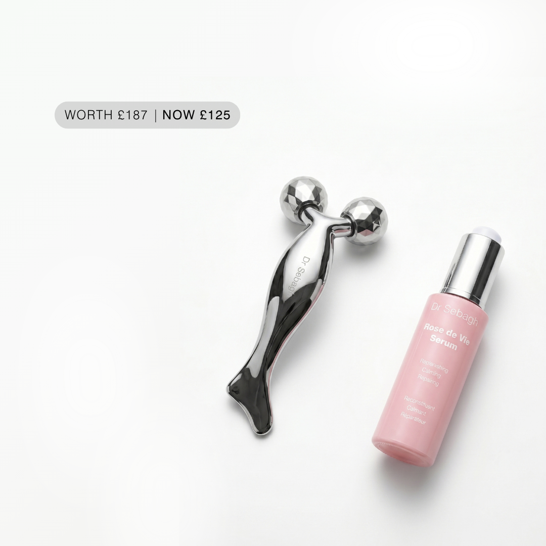 Pink serum bottle with silver cap and black and silver tool on a white background