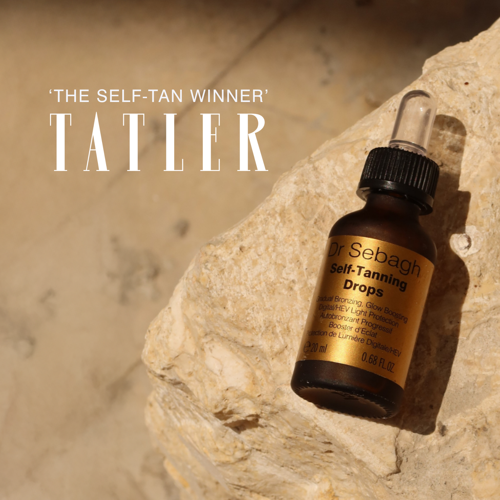 Dr Sebagh Self-Tanning Drops in an amber glass dropper bottle with a gold label, resting on a textured beige stone. Displaying the Self-Tanning Drops with the awarded 'The Self-Tan Winner' From Tatler.