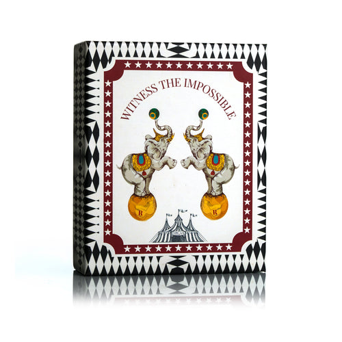 Dr Sebagh Christmas gift box with a black diamond border reading Witness the Impossible, with two circus elephants balancing on gold balls