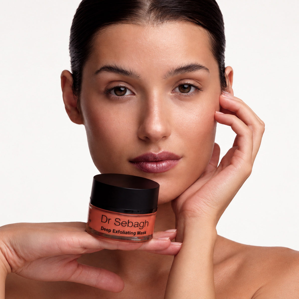 Model holding Dr Sebagh Deep Exfoliating Mask jar beneath her chin, showing smooth, glowing skin