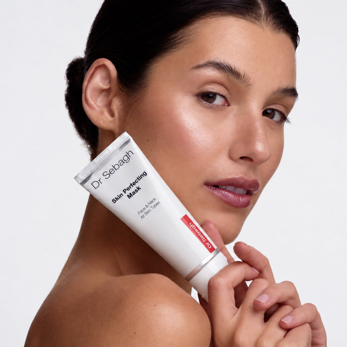 Model holding Dr Sebagh Skin Perfecting Mask tube against her cheek